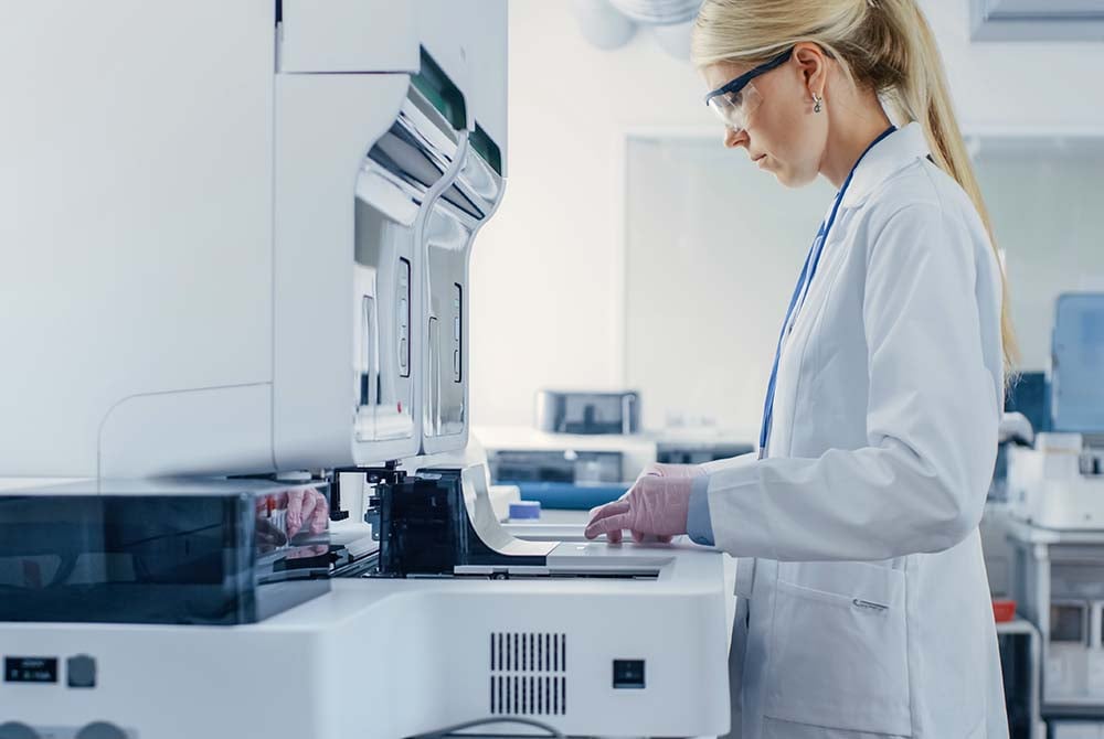 emale scientist in a lab coat operates a high-tech laboratory machine