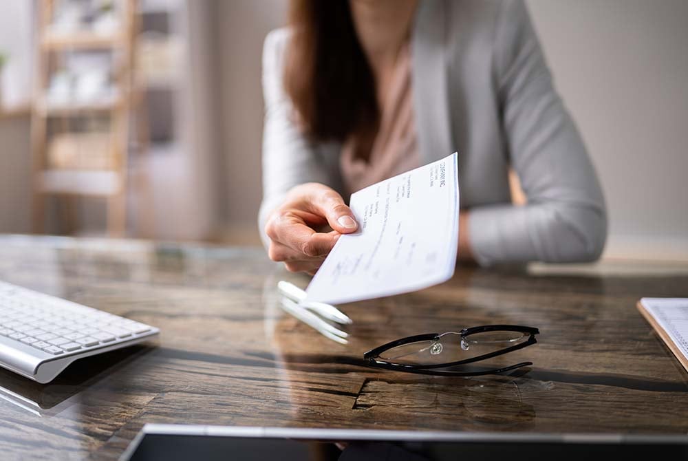 Businesswoman seated at a desk hands over a document
