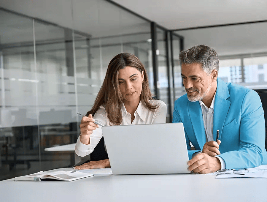 Woman pointing at a laptop screen with a pen while another person watches