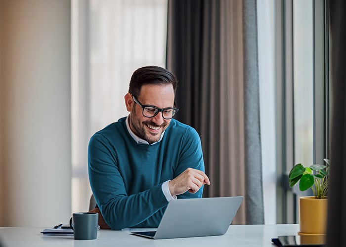 Man smiling while looking at a computer screen