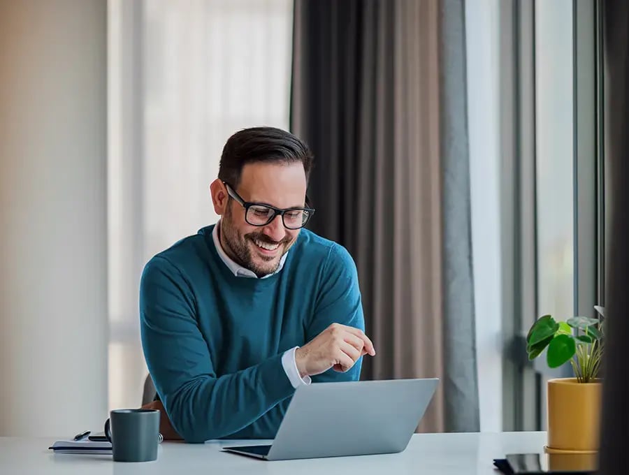 Man smiling while looking at a computer screen