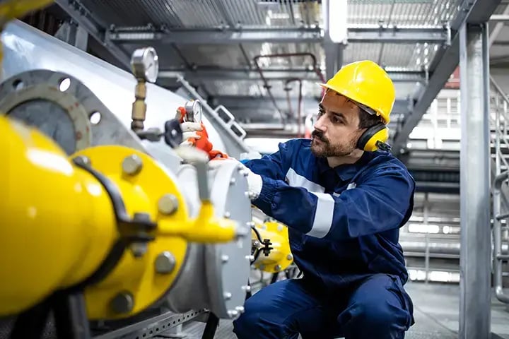 Industrial worker examining equipment in a gas refinery