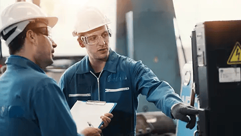 Group of engineers in blue uniforms with white hard hats and clear safety glasses supervising operations