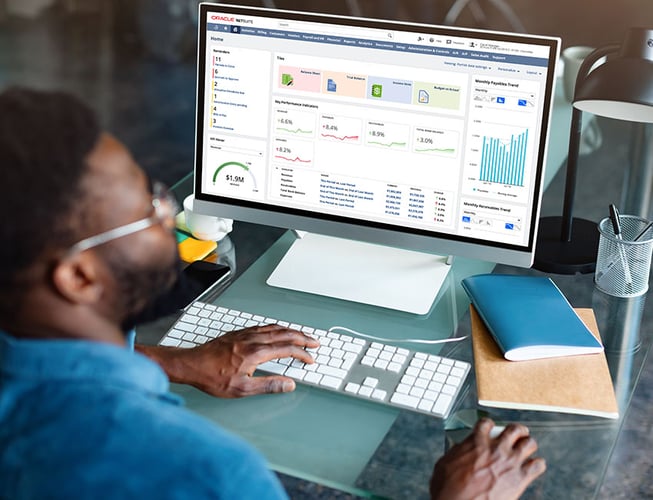 Man working on a desktop computer with NetSuite displayed on the screen