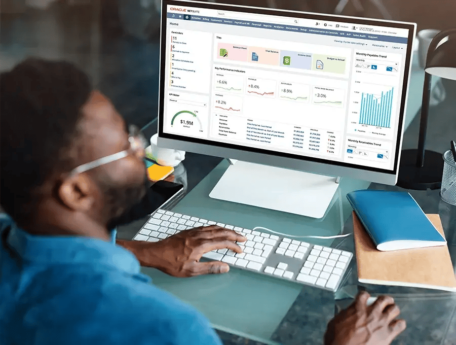 Man working on a desktop computer with NetSuite displayed on the screen