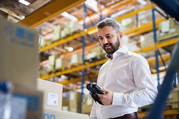 Man in a warehouse scanning a barcode with a scanner