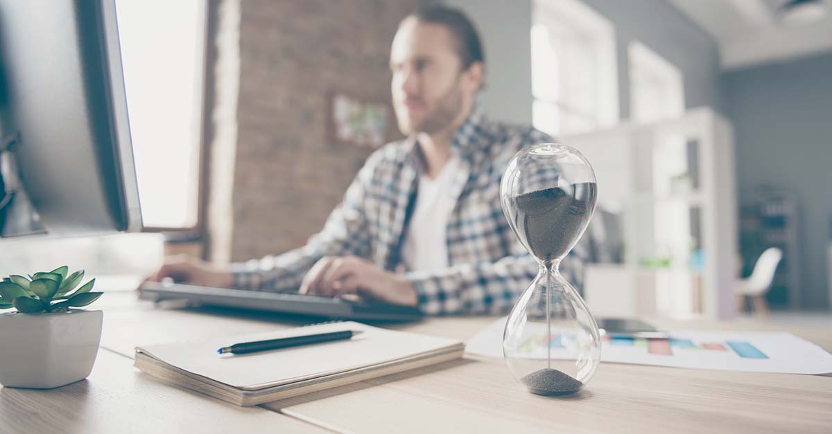 Man working with an hourglass on his desk